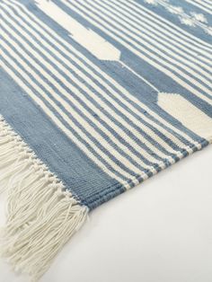 a blue and white striped rug with fringes on the bottom, in front of a white background