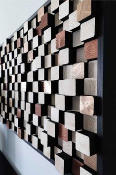 a wall sculpture made out of wood blocks on the side of a white and black wall