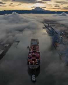 an aerial view of a large cargo ship in the ocean surrounded by low lying clouds