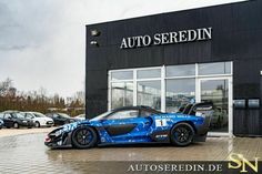 a blue sports car parked in front of a building