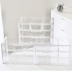 three clear plastic drawers are stacked on top of each other in front of a clock