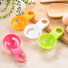 four plastic kitchen utensils sitting on top of a cutting board next to an egg