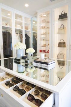 a white closet filled with lots of shoes and handbags next to a large mirror