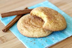 two cinnamon sugar cookies on a blue napkin with cinnamon sticks next to it and an orange spice stick