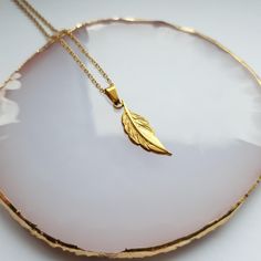 Gold Plated Feather Pendant. Size: Chain Length 45cm Material: 18K Gold Plated Stainless Steel ✨ Jewellery Care ✨ Even though our jewellery is waterproof, we do advise you to remove your jewellery before taking a swim. Salt and chlorine can react with the metals which can cause damage.   Your jewellery can also tarnish over time. This is a natural process caused by oxidisation and exposure to creams and perfumes. To get your jewellery back to its best, just give it a buff with a soft cloth. Gold Feather Necklace Perfect For Gifting, Feather Necklace Gift, Necklace Feather, Gold Feather Necklace For Gift, Peacock Feather Pendant, Feather Pendant Necklace, Feather Pendant, Gold Plated Necklace, Stainless Steel Jewelry