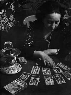 a woman sitting at a table with cards in front of her and an object on the table