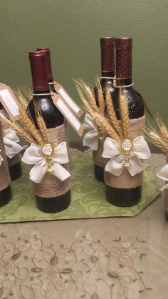 four wine bottles are decorated with burlocks and ribbons for the centerpieces