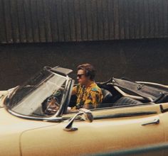 a man sitting in the driver's seat of a yellow convertible car