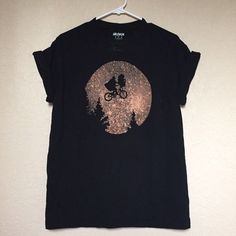 a t - shirt with a bicycle rider on it hanging from a hanger in front of a wall