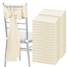 a stack of white chair covers next to a stack of chairs with bows on them