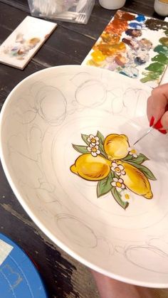 a woman is painting on a plate with yellow flowers