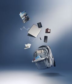 a backpack flying through the air with various items coming out of it