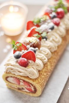 there is a pastry with fruit on it and cream frosting in the shape of a roll