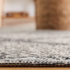 an area rug with black and white designs on the floor in front of a wooden table