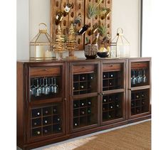 a wooden cabinet with wine glasses and bottles on it in front of a wall mounted art piece