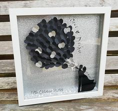 a white frame holding a black and silver paper cutout in the shape of a flower