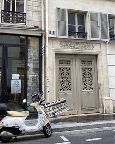 a motor scooter parked in front of a building with shutters on the windows