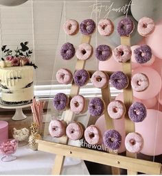 a table topped with lots of doughnuts on top of wooden sticks next to a cake