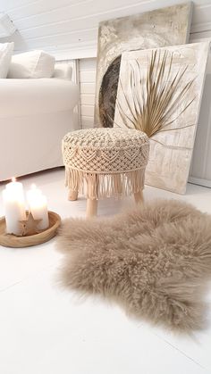 a living room with white furniture and fur rugs on the floor next to two candles