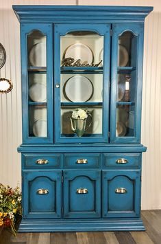 a blue china cabinet sitting on top of a hard wood floor