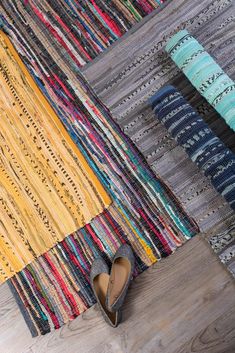 a pair of shoes sitting on top of a wooden floor next to colorful rugs