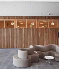 an empty room with couches, tables and chairs in front of a wood paneled wall