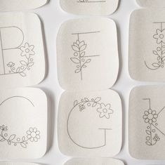 nine handmade coasters with flowers and letters drawn on them are arranged in rows