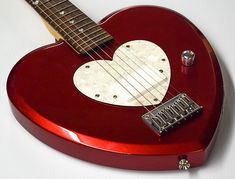 a red guitar with a white heart on it's back and neck is shown