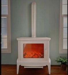 a small white stove in a room with wood floors and blue walls, along with a potted plant