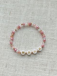 Mommy and Littles Co pink mama bracelet. Details: *4mm seed beads. *acrylic gold and white letter beads. *3 mm 14k gold plated beads. *Made with jewelry quality elastic. *please message if you are needing a size that is not listed! *NOTE: this listing is for ONE bracelet. Mama Bracelet Beads, Personalized White Beaded Bracelets For Mother's Day, Handmade White Beaded Bracelets For Mother's Day, Handmade White Friendship Bracelets For Mother's Day, Handmade Rose Gold Bracelets For Mother's Day, White Beaded Name Bracelet For Personalized Gift, Beaded Heishi Beads Name Bracelet For Gift, Beaded Heishi Name Bracelet As Gift, Personalized White Beaded Name Bracelet