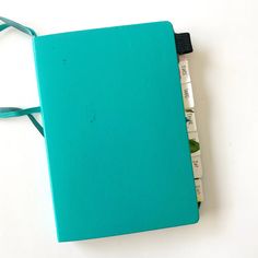 a blue notebook with two pens attached to it