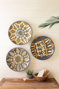 three decorative plates mounted on the wall above a wooden table with a potted plant