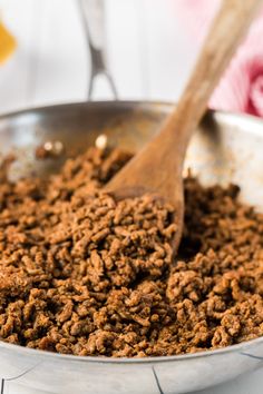 a wooden spoon in a metal pan filled with food