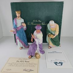 three figurines sitting on top of a table next to an envelope and certificate