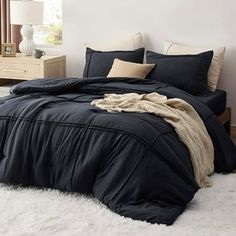 a bed with black comforter and pillows on top of white fluffy carpeted floor