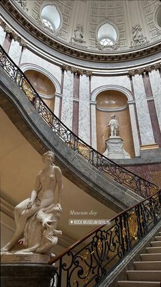 a statue sitting on top of a stair case next to a banister in a building