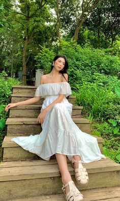 a woman in a white dress sitting on some steps