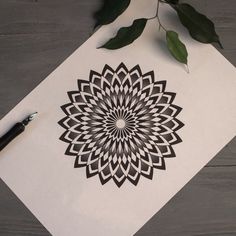 a white piece of paper sitting on top of a wooden table next to a pen