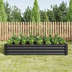 a large black planter sitting on top of a lush green field next to a wooden fence