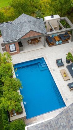 an aerial view of a house with a pool in the yard and lounge chairs around it