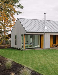 a house with a metal roof sitting on top of a lush green field