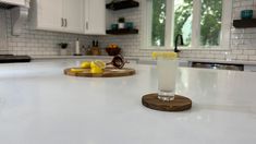 a drink sitting on top of a kitchen counter next to a cutting board with lemons