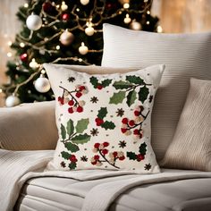 a christmas tree is in the background behind a couch with a pillow and throw pillows on it