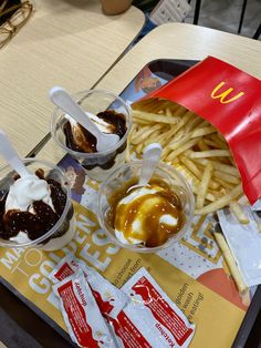 some food is sitting on a table with french fries and ketchup in containers