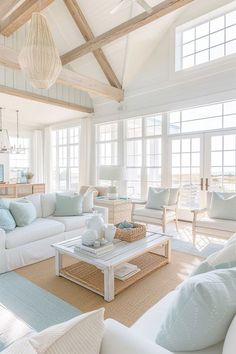 a living room filled with white furniture and lots of windows covered in wood beams