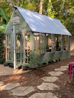 a small green house sitting in the middle of a yard with stepping stones on the ground