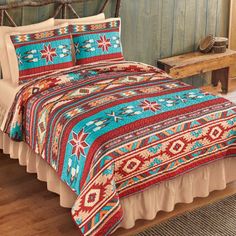 a bed covered in a colorful blanket next to a wooden headboard and foot board