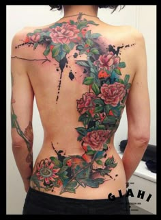 the back of a woman's body is covered in tattoos and flowers on her left side