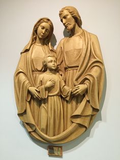 a statue of the virgin mary and child jesus in front of a wall with a plaque on it