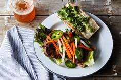 a white plate topped with meat and veggies next to a glass of beer